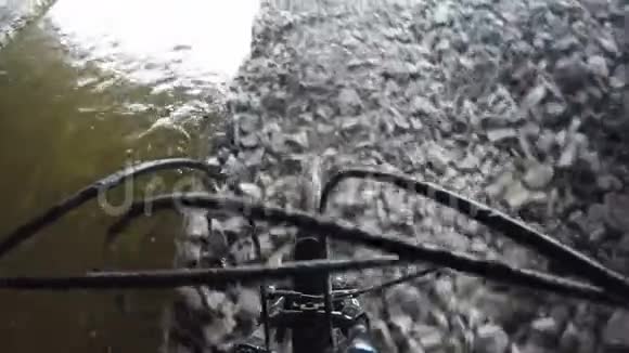 一个运动员沿着桥下的小溪滚动一辆自行车视频的预览图