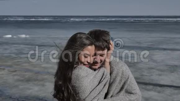 年轻夫妇拥抱着背景是一条覆盖着冰的河流阳光明媚的春天视频的预览图