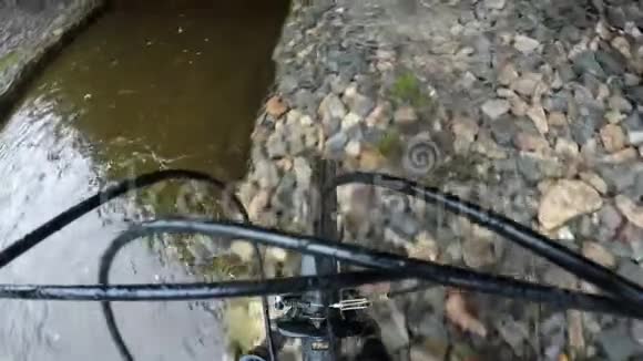 一个运动员沿着桥下的小溪沿着大堤滚动自行车视频的预览图