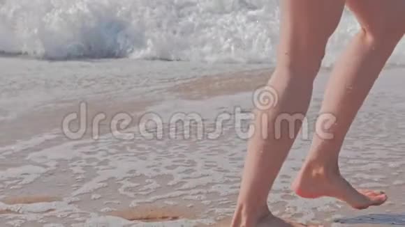 女人在海滩上行走在波涛汹涌的海洋中奔跑视频的预览图
