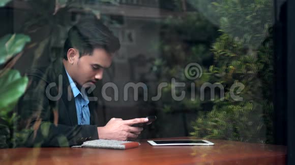 这位帅哥在玻璃窗附近用智能手机视频的预览图