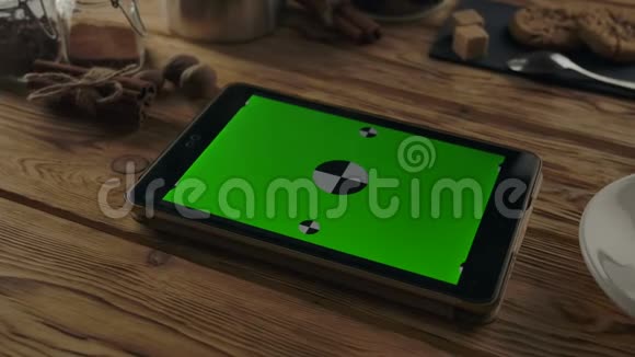 水平绿色屏幕平板电脑在木桌上靠近咖啡杯的木桌上视频的预览图