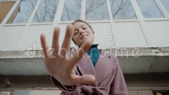 紫丁香外套的女孩站在老楼的背景下伸出手来把注意力集中起来关于视频的预览图