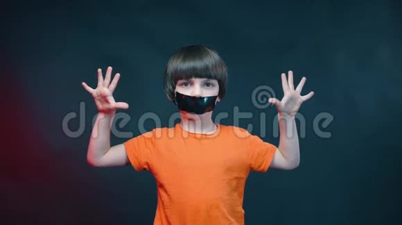 一个嘴巴紧闭的男孩在黑色背景上露出手掌视频的预览图