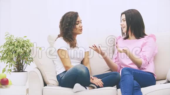 两个女朋友在温暖的家环境中坐在沙发上说话给了五个笑得可爱视频的预览图