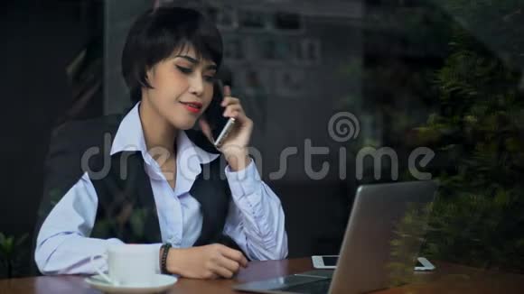年轻女商人用智能手机和二手电脑说话视频的预览图