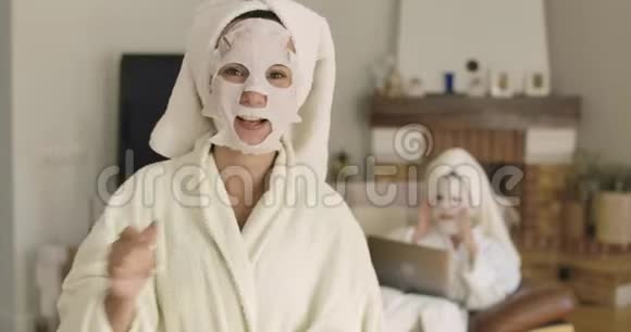 白种人开朗的女人带着面具回头看朋友或妹妹对着镜头做鬼脸的肖像视频的预览图