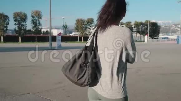 带着健身包走在街上的年轻女子视频的预览图
