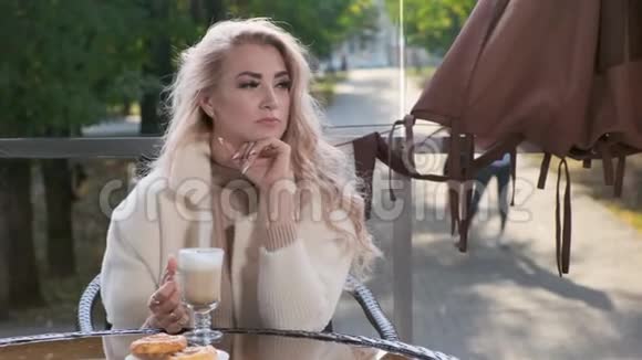 优雅的女人坐在街头咖啡馆里喝咖啡视频的预览图