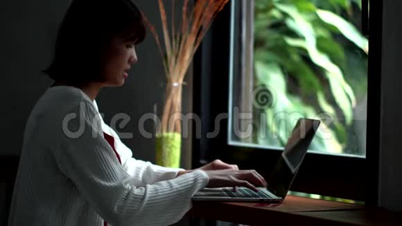 在咖啡店里坐着打手提电脑的年轻女子视频的预览图