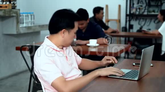 年轻人在咖啡馆里用笔记本电脑喝热咖啡视频的预览图