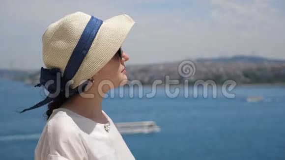 女人站在半张脸上享受着对海景的度假视频的预览图