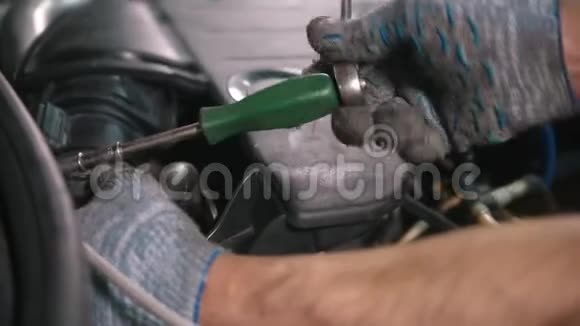 汽车修理店工人在汽车罩下用螺丝刀工作视频的预览图