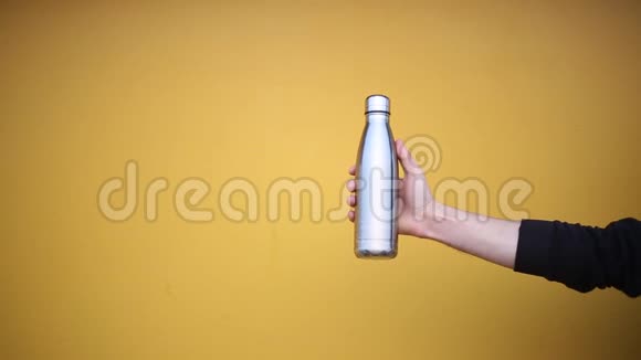 男性手拿一个钢制的生态热瓶用于黄色背景下的水视频的预览图