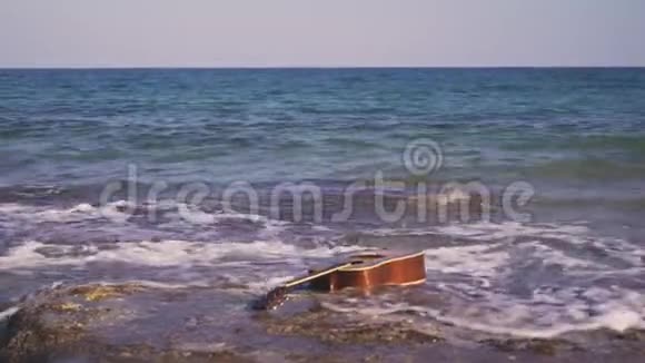 声波吉他漂浮游泳漂流在海中或海洋中波浪海浪把吉他扔在岸边或海滩上视频的预览图