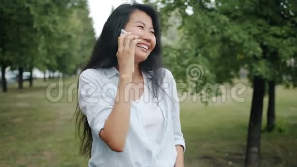 亚洲学生在绿色公园里用手机笑着吃鱼翅视频的预览图