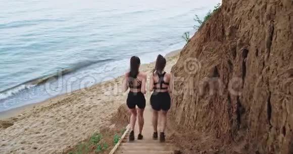 女朋友互相跑步两个身材匀称的迷人女孩都穿着深色运动服视频的预览图