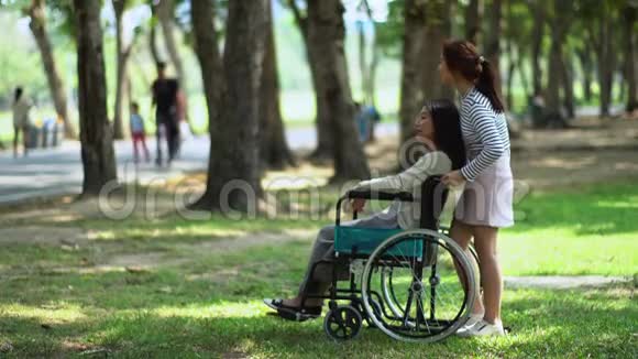在公园坐轮椅的漂亮少女和母亲视频的预览图