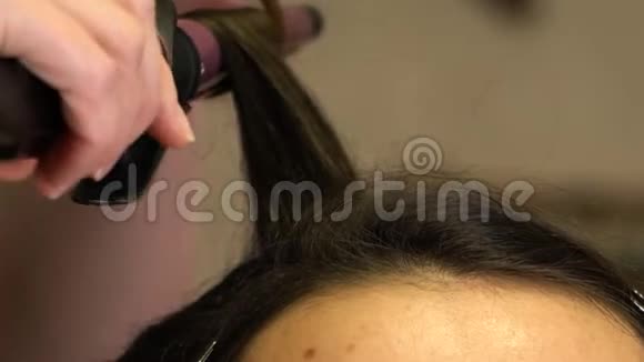 造型师用卷发器女孩的头发卷曲视频的预览图