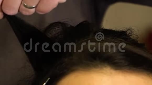 造型师梳理一个黑发女孩的卷发视频的预览图