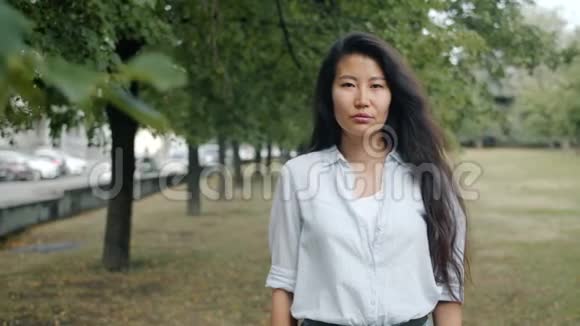 严肃的亚洲女商人独自站在城市公园的肖像视频的预览图