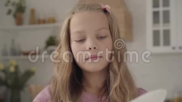 一个年轻疲惫的白种人十几岁的女孩穿着粉红色的连衣裙擦拭盘子看着远处叹了口气勤奋视频的预览图