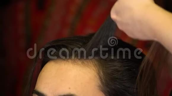 这位造型师卷起一缕头发把她的头发缠绕在一根烫卷的熨斗上视频的预览图