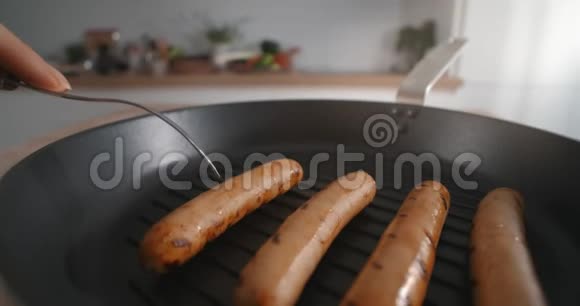 烤香肠是用叉子从热锅里取出的烤香肠用肉制品煮热狗煮熟的视频的预览图