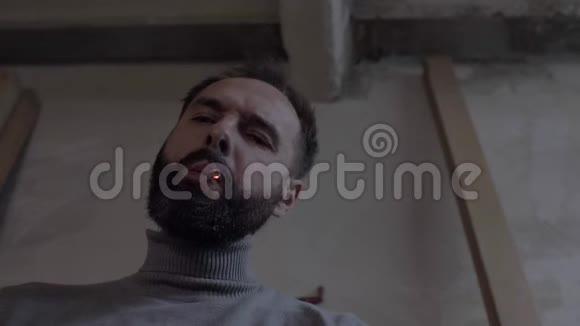 一个长着大胡子的人的肖像迷人的胡须男在黑暗中抽烟4k4k录像慢动作2398fps视频的预览图