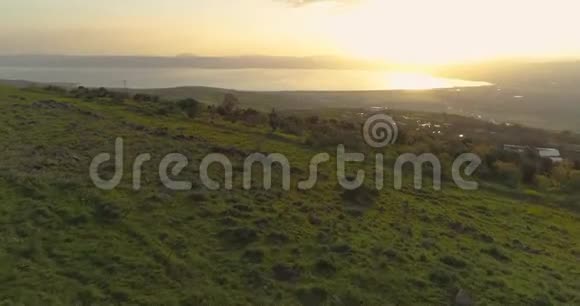 在戈兰高地和以色列北部的泰伯里亚上空的日落处进行空中射击开阔的田野有橙色的绿色景观和视频的预览图