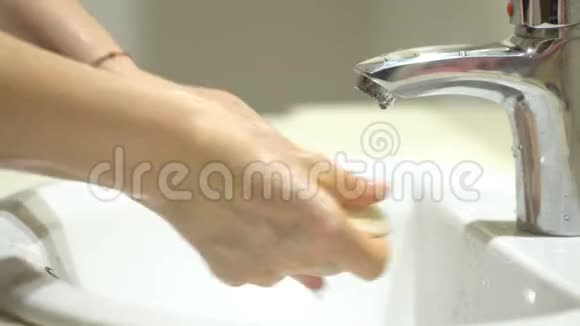 美丽女人的双手用泡沫洗手池洗手洗皮肤水从手中流过视频的预览图