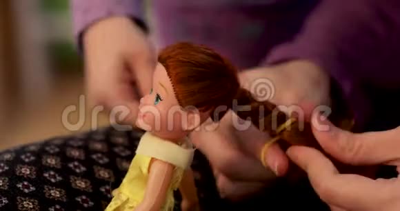 一位母亲用手刷牙整理她的小女儿娃娃的头发视频的预览图