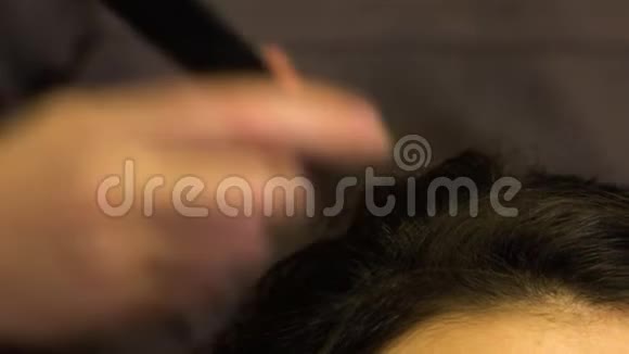 造型师梳出一个黑发女孩卷曲的头发视频的预览图
