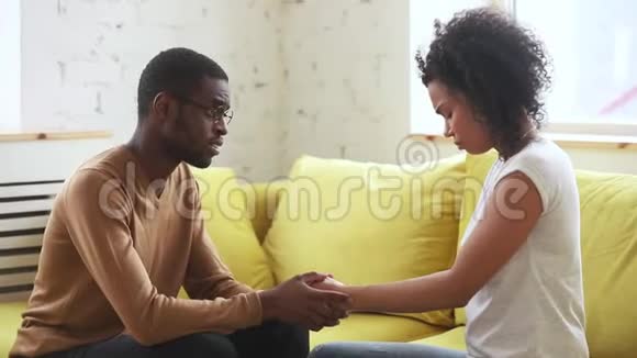 坐在沙发上支持伤心妻子的非洲丈夫视频的预览图