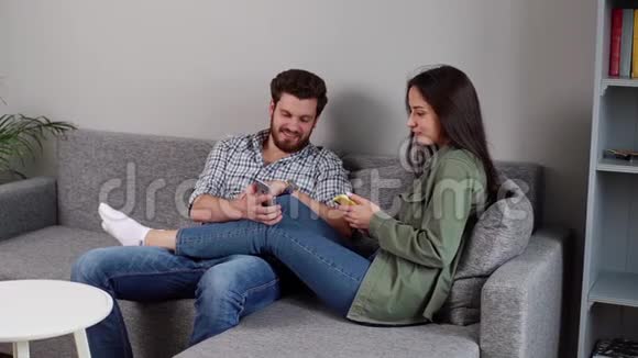 可爱积极的年轻夫妇微笑着看着智能手机视频的预览图