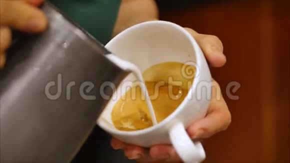 专业咖啡师制作新鲜的磨碎咖啡咖啡师制作拉丁艺术将牛奶倒入杯子同时制作视频的预览图