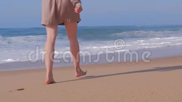 女人在海滩上散步海浪视频的预览图