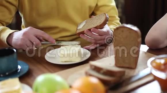 一个男人在早餐时做三明治在早晨切面包抹黄油放奶酪视频的预览图