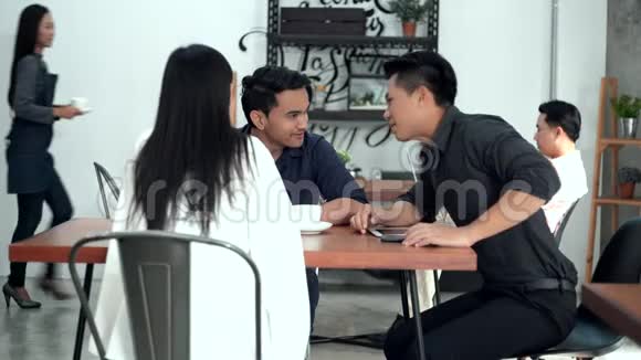 三个年轻的同事在咖啡店里讨论视频的预览图