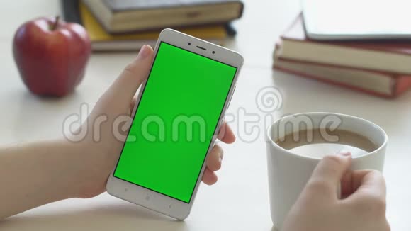 查看女士手持色度键绿色屏幕智能手机观看内容无需触摸或滑动喜欢喝酒视频的预览图