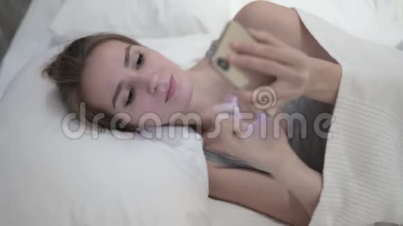 美女在床上用智能手机视频的预览图