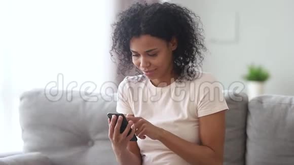 带着智能手机的非洲女人笑着读轶事感觉欣喜若狂视频的预览图