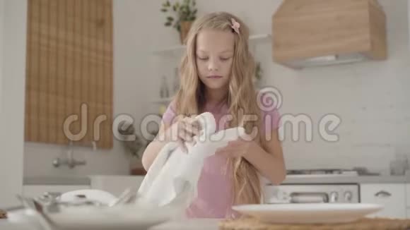 年轻愤怒的白种人十几岁的女孩穿着粉红色的连衣裙擦拭盘子愤怒地把它放在桌子上金发碧眼视频的预览图
