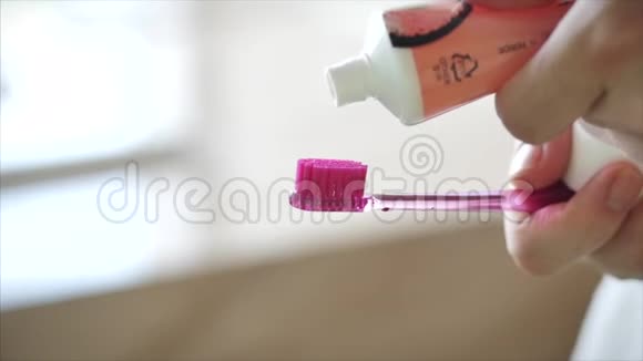 一只雌性的手把彩色牙膏挤到粉红色牙刷上现代浴室的口腔卫生特写镜头视频的预览图