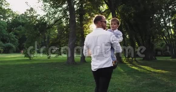 一个非常可爱的男孩和他的爸爸在公园里玩得很开心一起笑视频的预览图