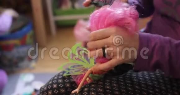 一位母亲用手刷牙整理她的小女儿娃娃的头发视频的预览图