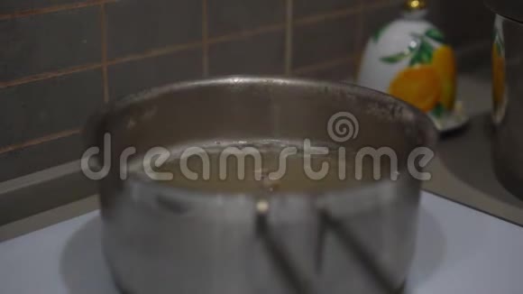 家庭主妇用汤匙在锅里搅拌汤视频的预览图