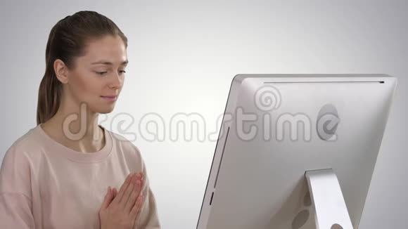 坐在桌子旁边的椅子上电脑在梯度背景上冥想的迷人女人视频的预览图