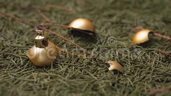破碎的金色圣诞球躺在干燥的落针和圣诞树的树枝上视频的预览图
