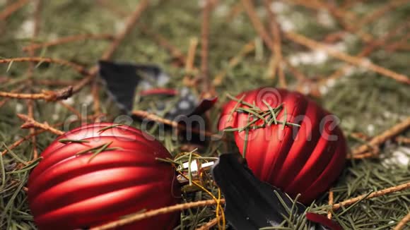 破碎的红色圣诞球躺在干燥的落针和圣诞树的树枝上视频的预览图